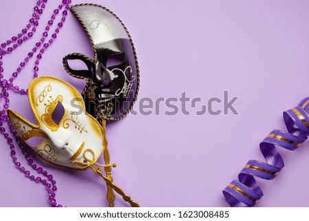 Two Venetian carnival masks are white and black on a lilac background. Mardi Gras concept