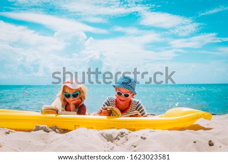 cute boy and girl read books on beach, family vacation
