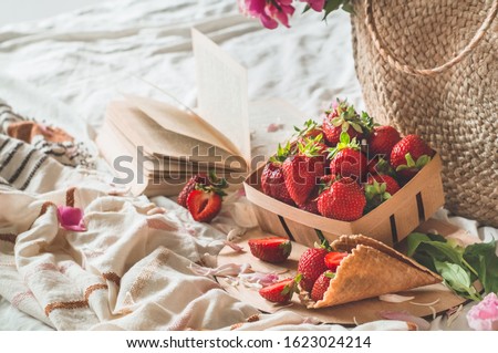 Still life details in home interior of living room. Basket with strawberries Pions flowers and spring decor on the books. Read, Rest. Cozy spring Summer concept.