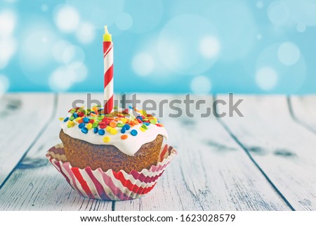 Delicious birthday cupcake on blue background.Muffin birthday with a candle on a blue background, bokeh effect, copy space. Beautiful birthday card with sweets.