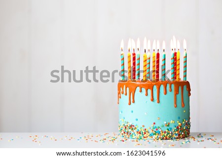 Colorful birthday cake with lots of candles and orange drip icing