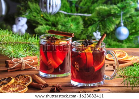 Christmas mulled red wine glühwine with aromatic spices and citrus fruits on a wooden rustic table, close-up. Traditional hot drink or festive cocktail at Christmas or New Year time.