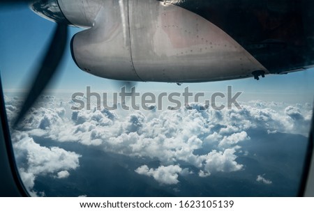 Twin-engine short-range plane engine propeller during the flight to Lukla airport over the Himalayas peaks. Aircraft cabine window view.