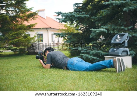 videographer laying on green grass with camera at yard