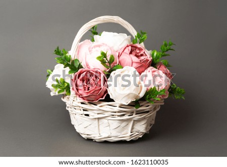 Flowers in bloom: Bouquet of pink and white peonies in a straw basket on a gray background.