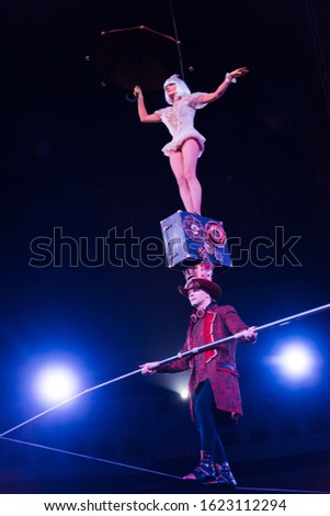 low angle view of man holding pole and supporting attractive acrobat while walking on rope