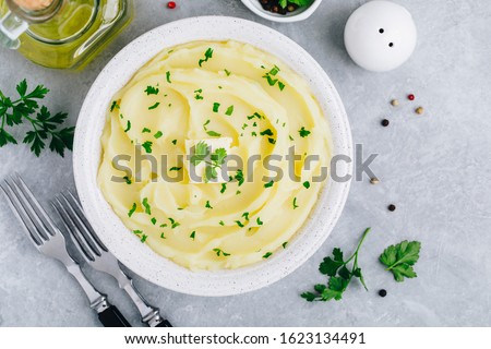 Mashed Potatoes with butter and fresh parsley in a white bowl on gray stone concrete background. Top view, copy space Royalty-Free Stock Photo #1623134491
