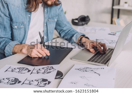 cropped view of animator using gadgets near sketches