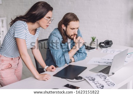 animators looking at laptop near sketches on table