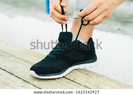 A young woman sitting on a bench and tying her shoelaces in the fresh air