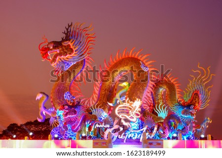 Chinese dragon statue on twilight golden sky, Translation of text appear in image means Lantern puppet festival.