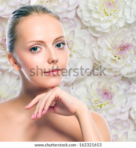 Young girl against white flowers background. Perfect skin and clean beauty make-up. Dahlia flowers. Beauty concept