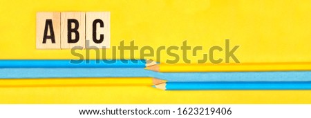 panorama background. ABC letters of wooden blocks and multicolored pencils on a yellow and light blue universal two tones paper background. panoramic view of School begginning. back to school project