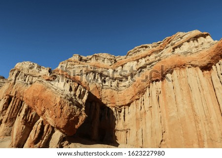Low angle landscape of large vertical yellow and orange stone formations at Red Rock State Park in California
