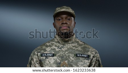 African American young happy man soldier of USA in uniform and hat tapping and texting on the smartphone with a smile.