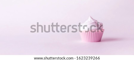 on a pink background is a beautiful pink cupcake with airy white whipped cream