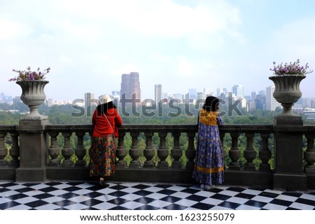 Two Asian female tourists posing for a picture on a balcony overlooking the Bosque de Chapultepec or Chapultepec Forest from Chapultepec Castle in Mexico City, Mexico.