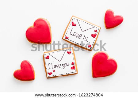 Valentine's Day. Gingerbread cookies in the shape of a red heart, 
with the image of a couple in love and a love letter.White background top view,flat lay, mockup