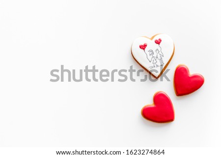Valentine's Day. Gingerbread cookies in the shape of a red heart, 
with the image of a couple in love and a love letter.White background top view,flat lay, mockup