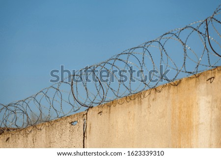 Spiral barbed wire close-up. Conclusion, restriction of freedom. Barbed wire on a concrete fence