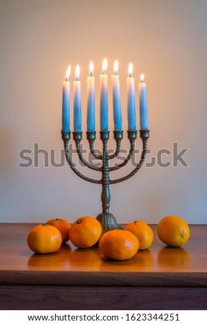 traditional Jewish menorah with burning candles and tangerines in a wooden table for the celebration of Hanukkah.