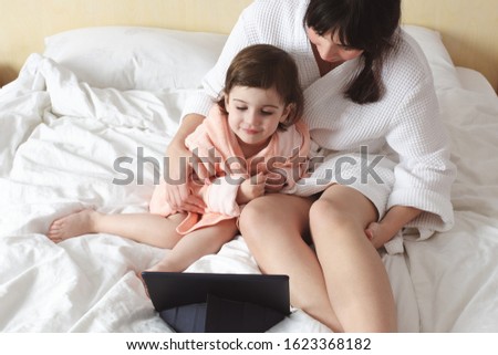 Cute family using digital talet pc on the morning in the bedroom.