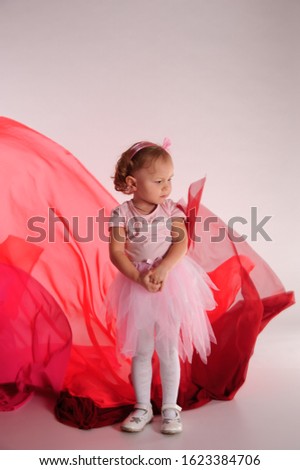 little girl in a pink dress in the studio and flying fabric