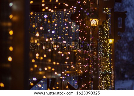 Wooden porch decorated with a garland and burning lanterns against the background of winter twilight