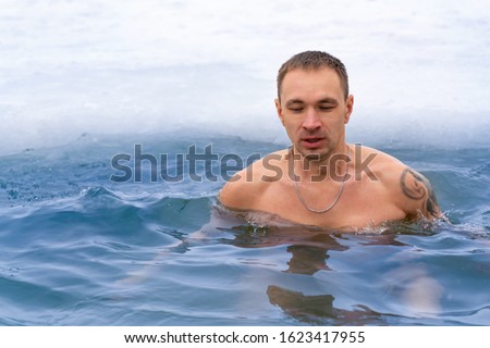 A man plunges into cold water in winter and takes his breath away