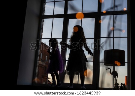 Silhouettes of two little girls playing in the window