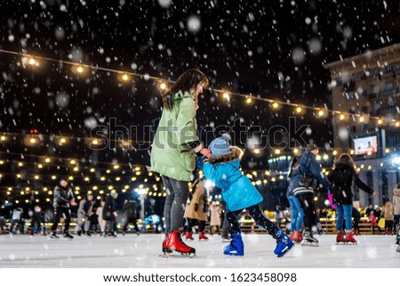 Skating rink. Mom with daughter at the ice rink. It snows.