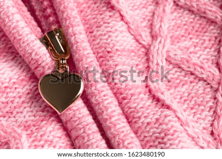Slider with shape of heart in zipper on textile woolen pink clothes