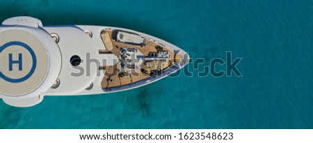 Aerial drone ultra wide photo of mega yacht nose docked in tropical exotic island bay with turquoise clear sea