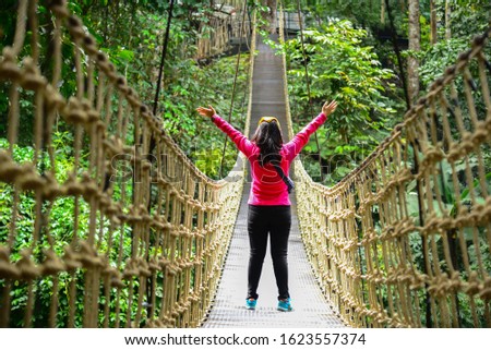 Young girl walking in Bridge Rainforest Suspension bridge, Crossing the river, ferriage in the woods. Royalty-Free Stock Photo #1623557374
