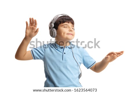 Cute little boy dancing with closed eyes and listening to music on headphones isolated on white background