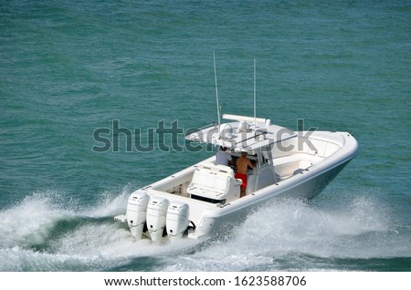 Angled overhead view of a white sport fishing boat powered by three outboard engines Royalty-Free Stock Photo #1623588706