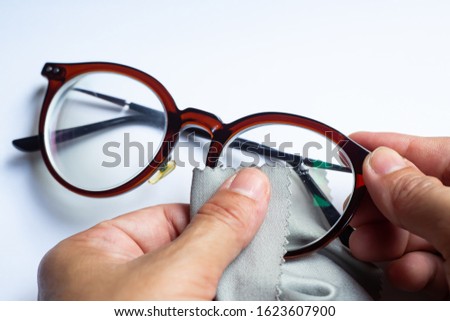 Woman's hands cleaning shortsighted or nearsighted eyeglasses by microfibre cleaning cloths, On white background, Close up & Macro shot, Selective focus, Optical concept Royalty-Free Stock Photo #1623607900