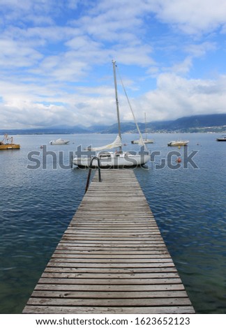 Lake Como (Italy). An idealistic picture - a wooden pier leads to a small white yacht.
