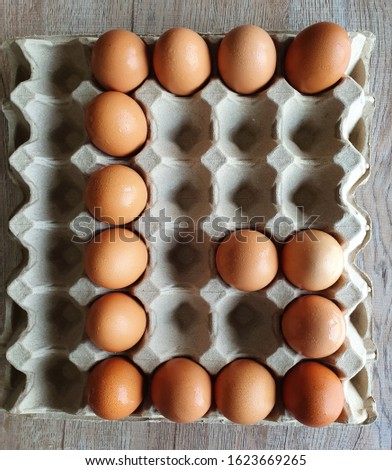Close-up view of raw brown chicken eggs in egg box on wooden background with "A to Z" collection as "G" alphabet