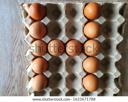 Close-up view of raw brown chicken eggs in egg box on wooden background with "A to Z" collection  as "H" alphabet