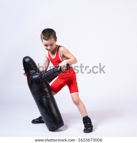 Cheerful sport boy in wrestling tights and wrestlers makes a throw through the back with a sporting dummy for training and handling techniques from various martial arts on a spruce isolated background
