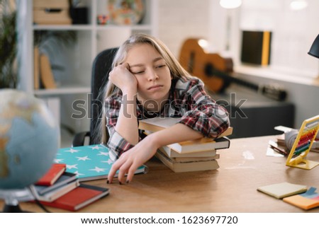 Tired schoolgirl sleeping on book. 