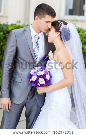 beautiful young bride and groom standing outdoors hugging and smiling