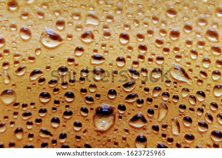 Drops of water on yellow surface. Macro photo, drop, shadow plastic base. Selective focus.