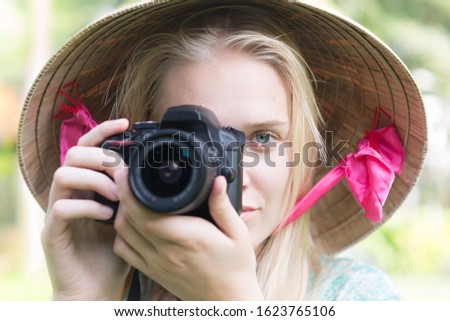 Female photographer taking a photo, looking into the camera. Travel and hobbies.