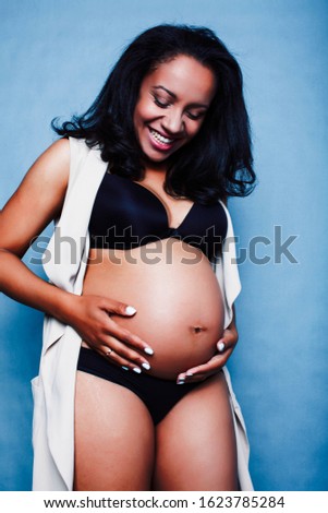 young pretty african american woman pregnant happy smiling, posing on blue background, lifestyle people concept copyspace