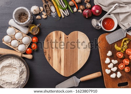 woman preparing a festive dinner for two in honor of Valentine's Day classic Italian pizza Margherita in the shape of a heart and mozzarella in the shape of a heart