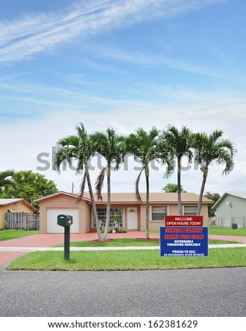 Welcome Open House Real Estate Sign Front Yard Lawn Suburban Ranch Style Home with Palm Trees Residential Neighborhood USA blue sky clouds