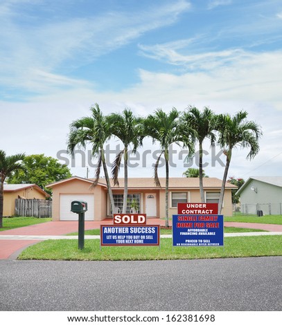 Sold Under Contract Real Estate Sign front yard lawn suburban ranch style home with palm trees Residential Neighborhood USA Blue Sky Clouds