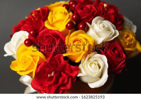 Flowers in bloom: A bouquet of red and yellow roses on a grey background.